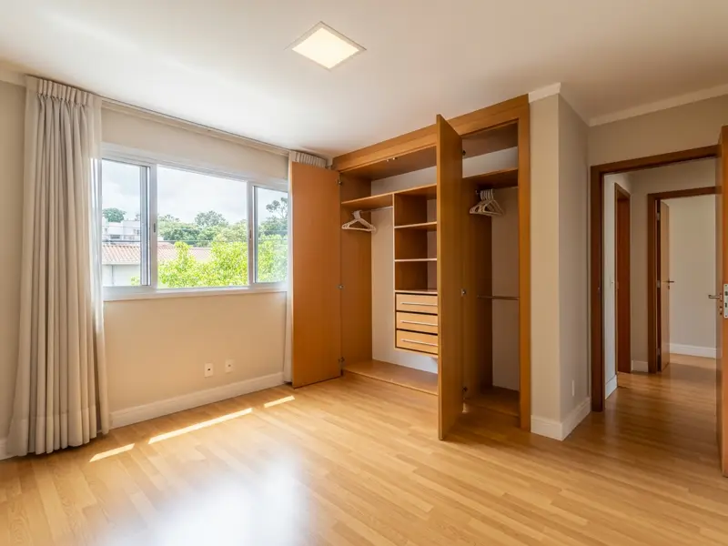 Sala vazia com piso de madeira e janela aberta